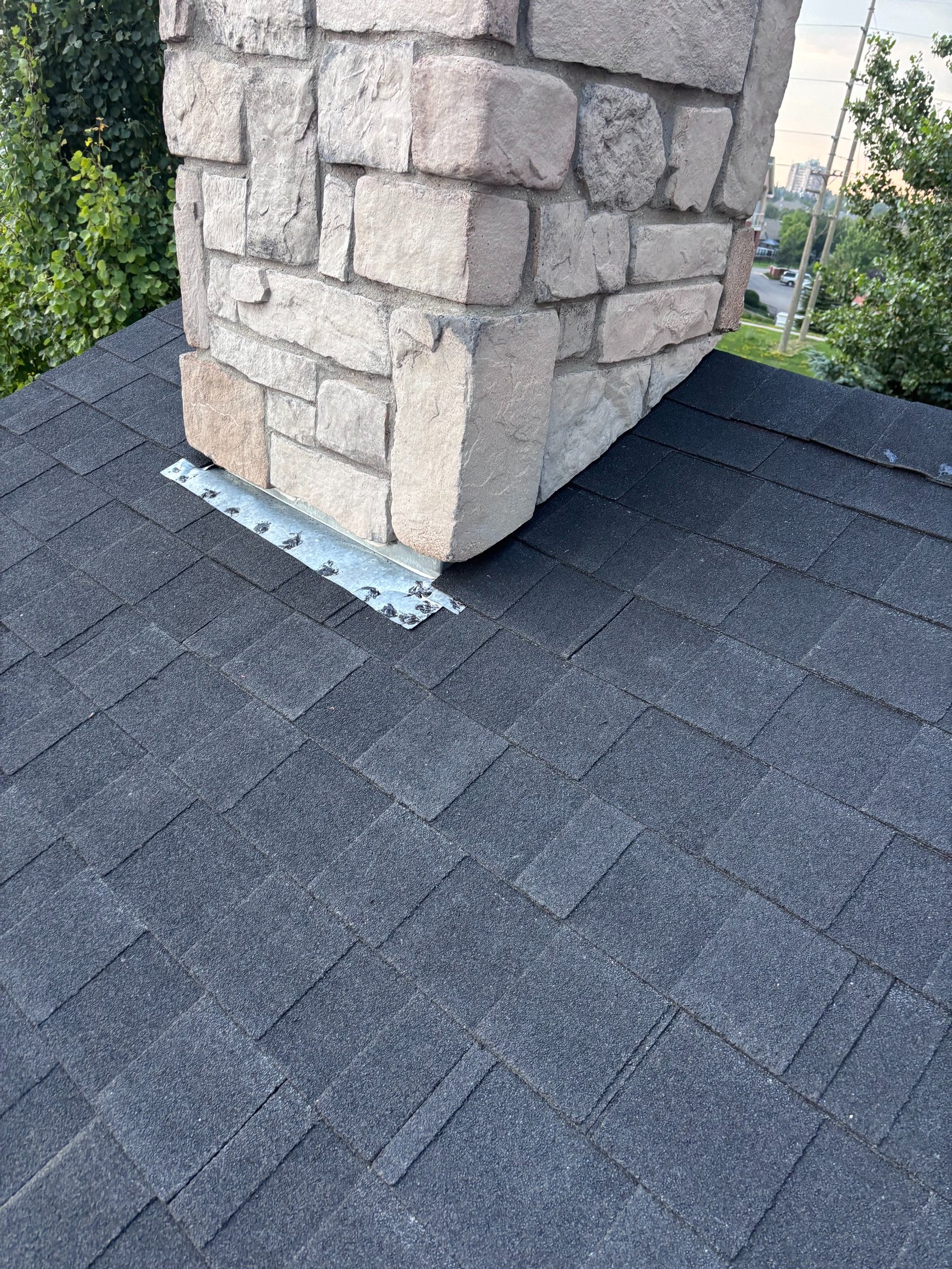 Close-up of new chimney flashing sealed into fresh dark shingles