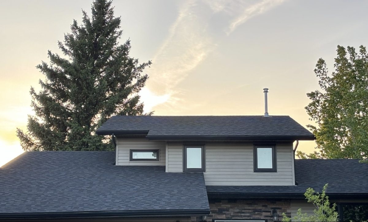 Saskatoon home with a new dark asphalt shingle roof installed by No Stress Roofing at sunset
