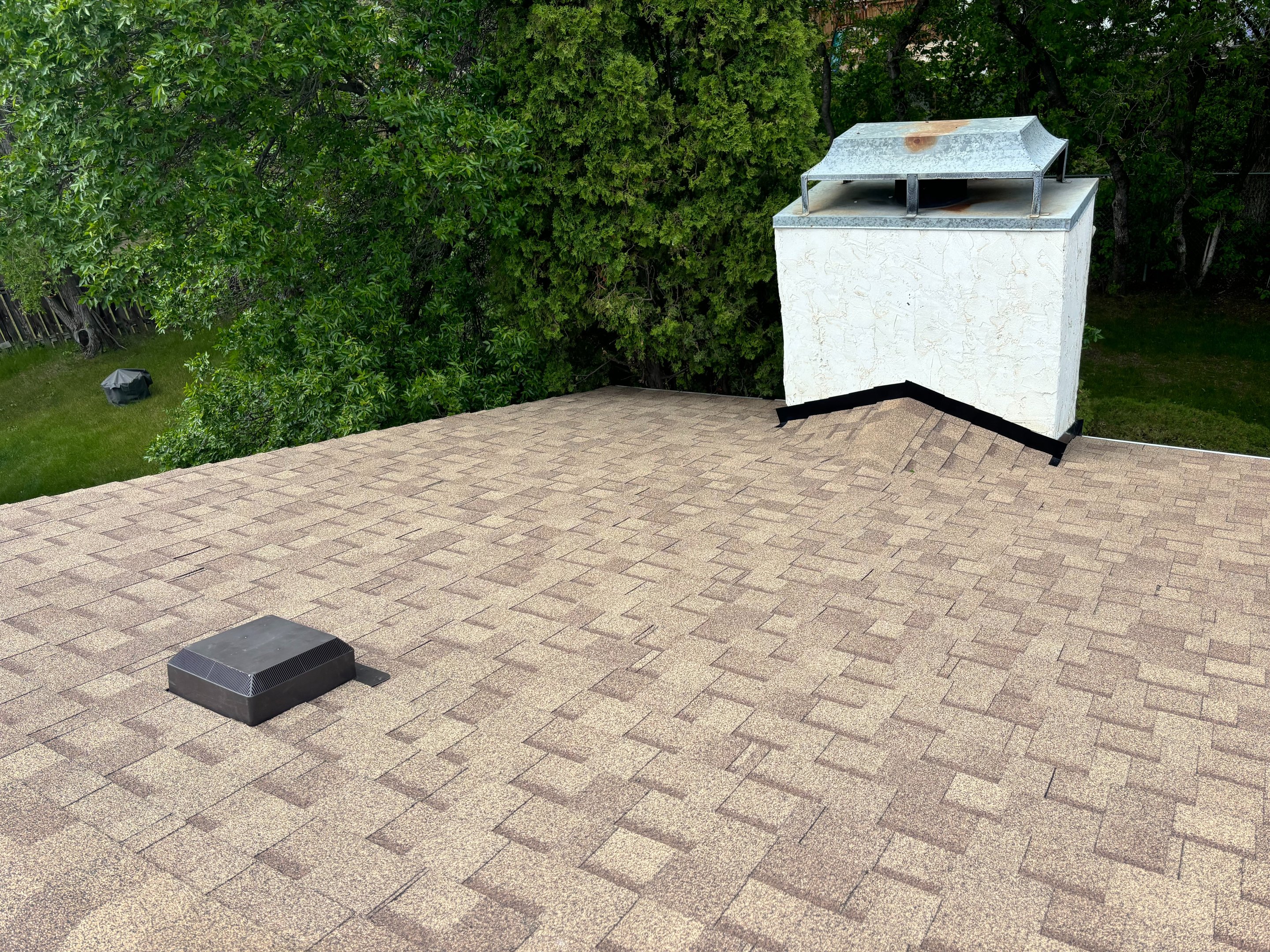 Brown asphalt shingle roof with a white chimney in Saskatoon