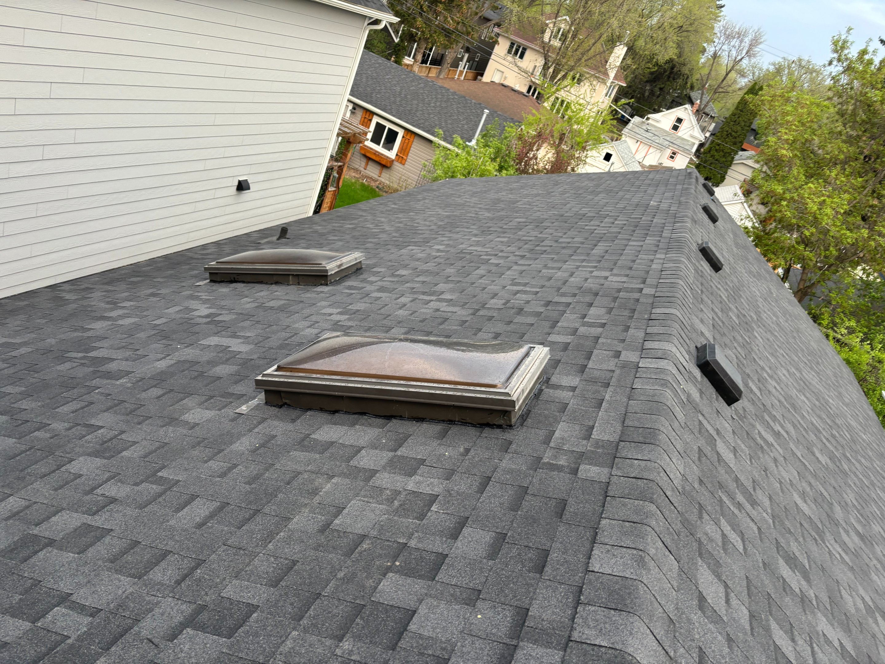New dark asphalt shingle roof with skylights installed by No Stress Roofing